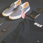 A modern collection of men's fashion essentials flat lay, featuring shoes, watch, phone, and eyewear for a sleek style.